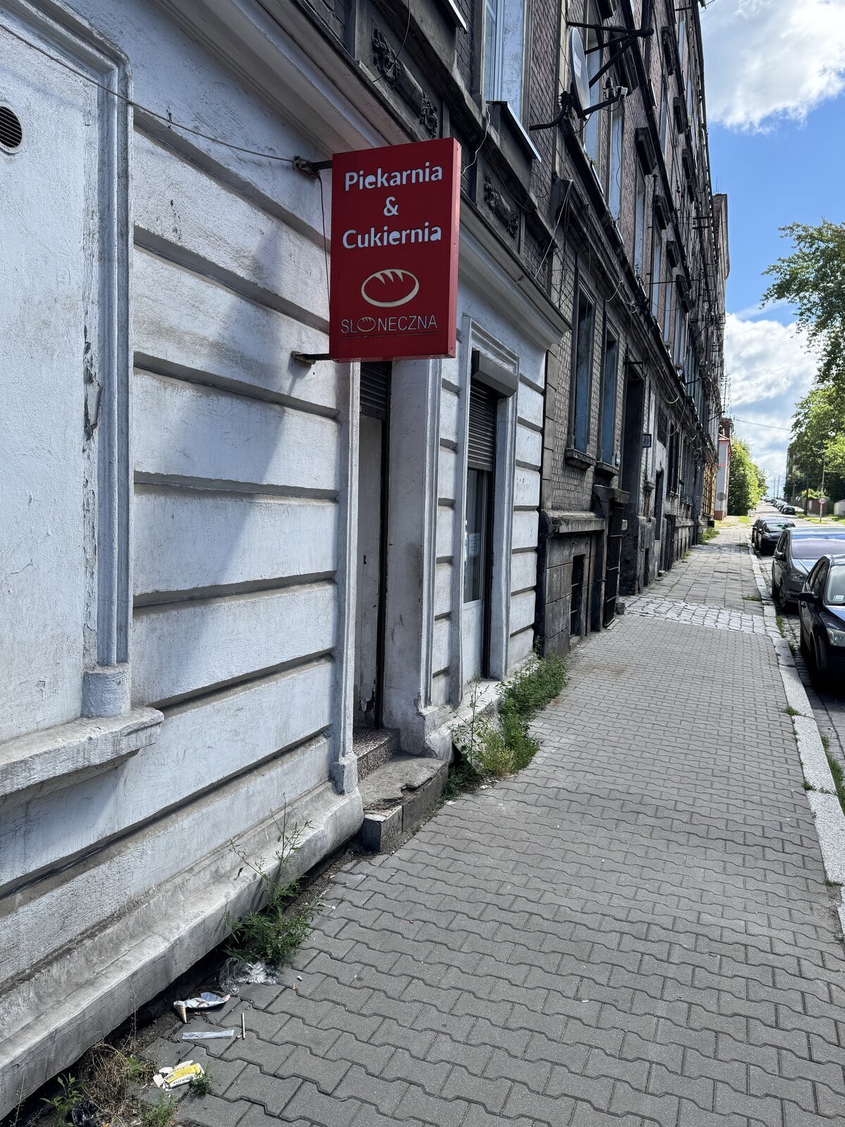 Wejście do piekarni Słoneczna przy Brzezińskiej 11 w Bytomiu z czerwonym szyldem na elewacji